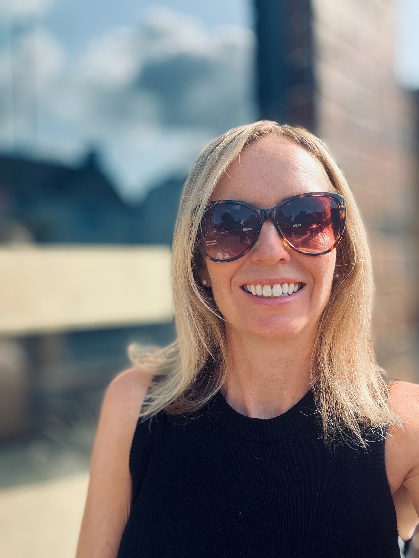 Leah smiling in sunglasses at a sunny legal community event